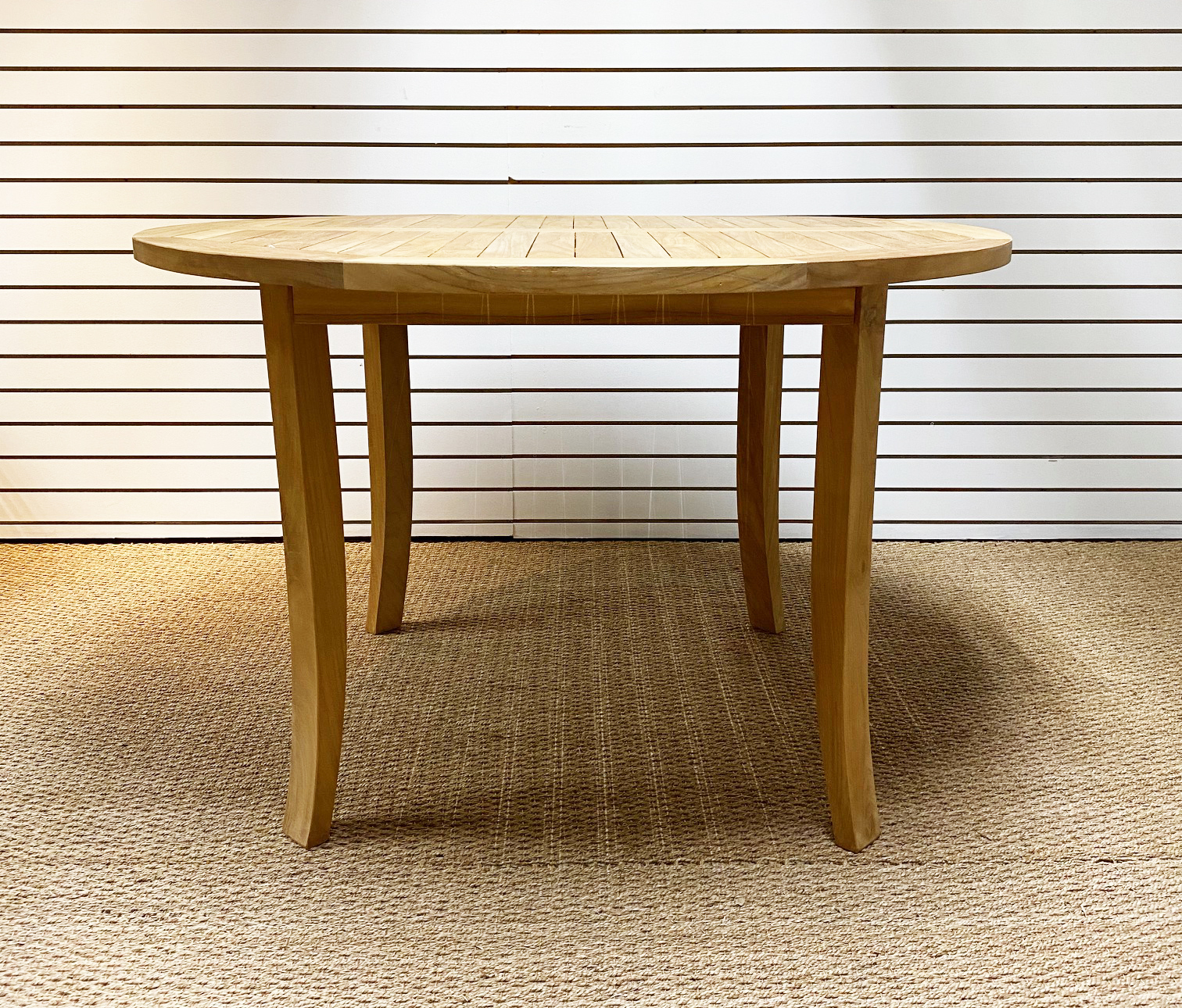The Lahaina Round Dining Table is a round, four-legged table with symmetrical teak slats across the top. It can look at home in a boho chic kitchen or as a contemporary furniture piece.