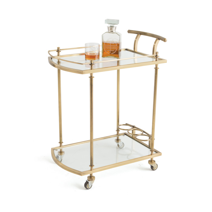 The Shurlock Bar Cart is made of polished brass with glass surfaces. It has wheels, a handle, and rounded bottle-holders built in. Complements vintage home decor. Charleston, SC residents can purchase locally.