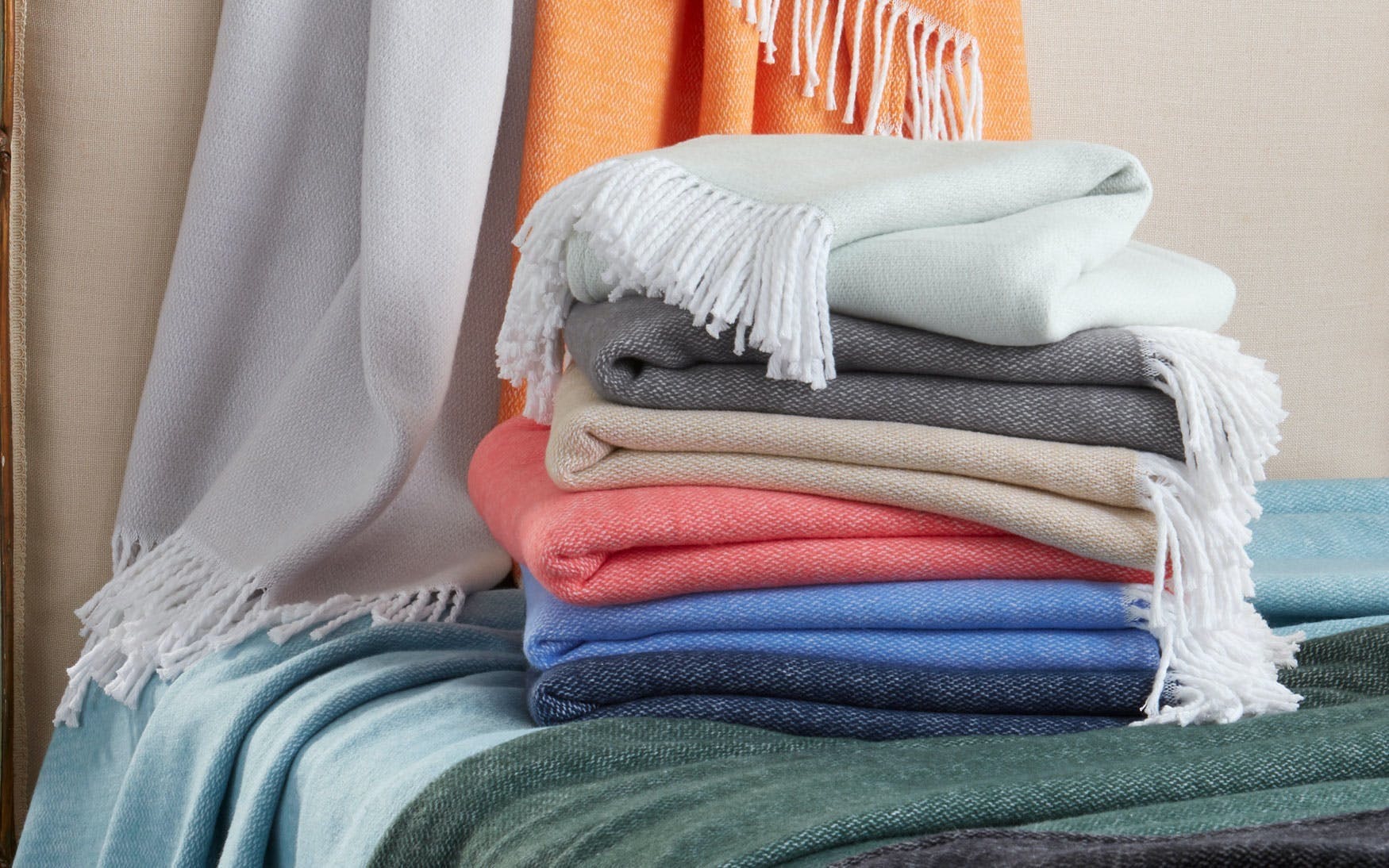 A stack of Pezzo Throw blankets in a range of colors from neutral to bold. Perfect for your Charleston, SC home decor.