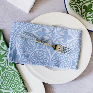 Blue and white damask-print cloth napkin folded on a white plate with a silver fork..