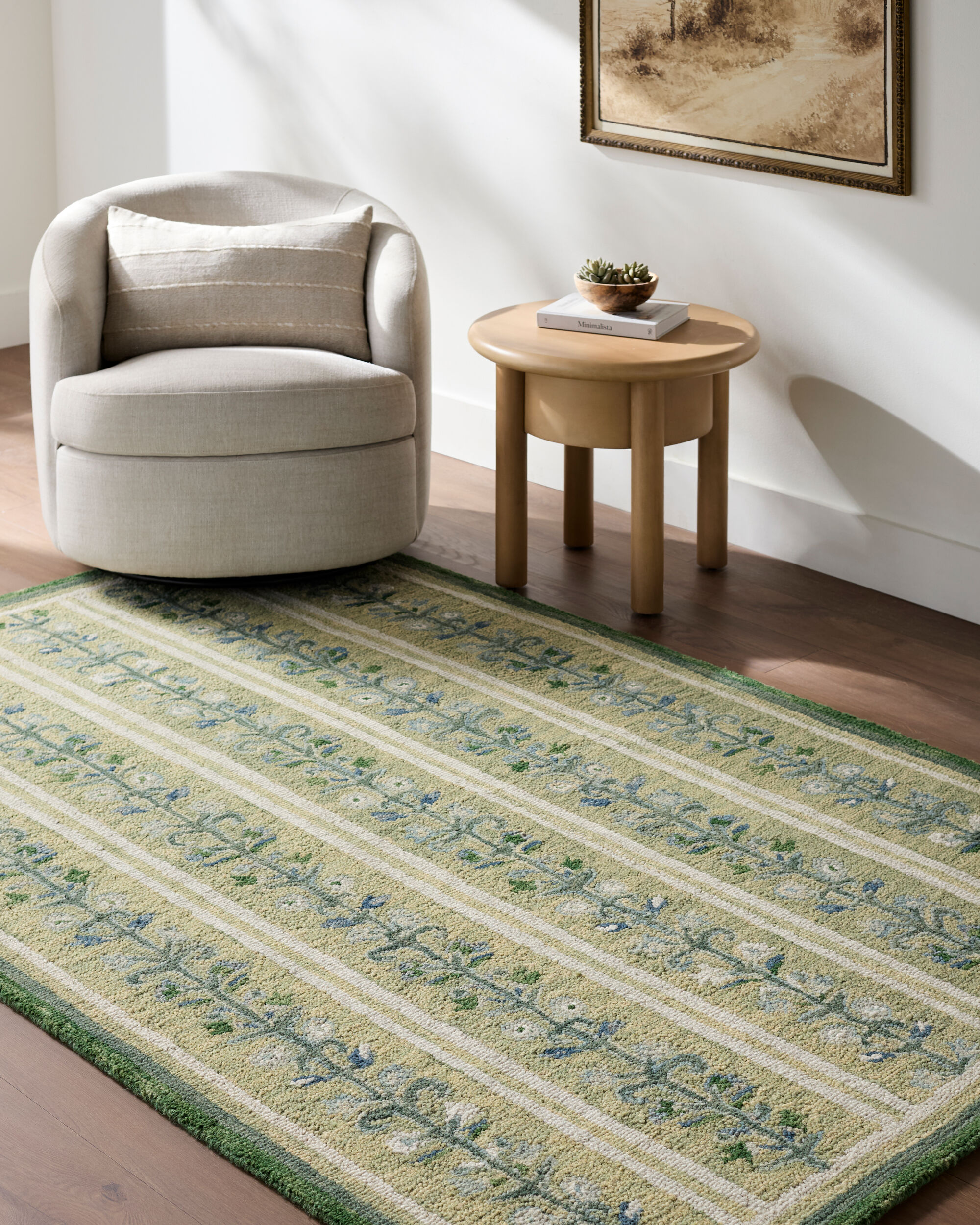 lifestyle image of hand tufted green rug with repeating blue and cream floral vine motifs, ivory stripes, and a dark green border