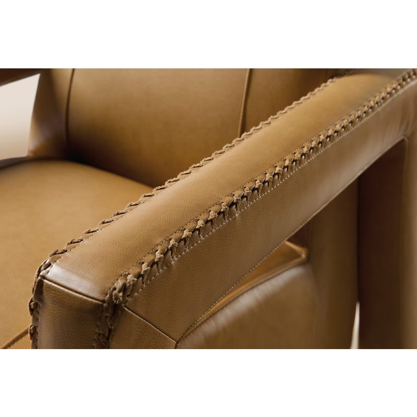 detail of the stitching on the arm of a tan leather chair