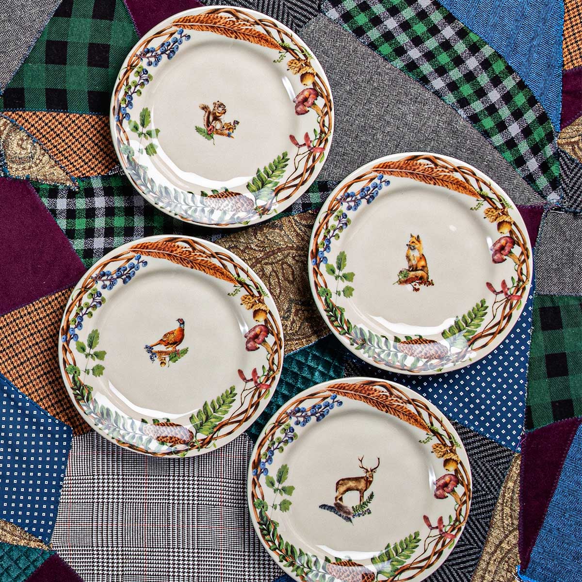 set of four salad plates with featured forest animals in the center and a woodland inspired border