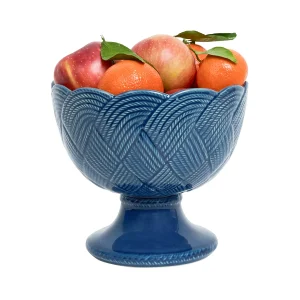deep blue footed bowl with intricate, interwoven braiding filled with apples and oranges