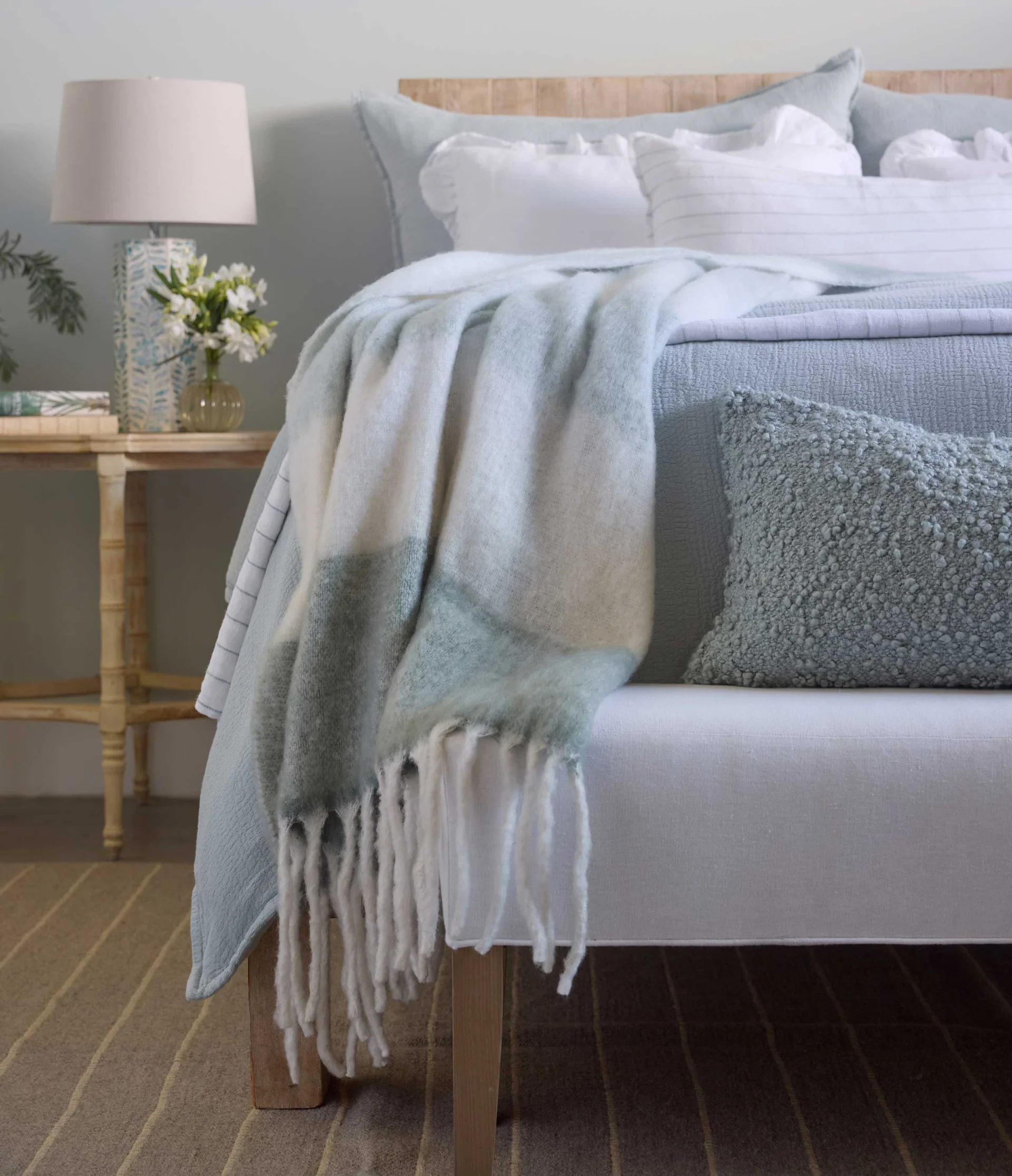 aqua striped faux mohair throw with ivory fringe draped on a bed with aqua linens