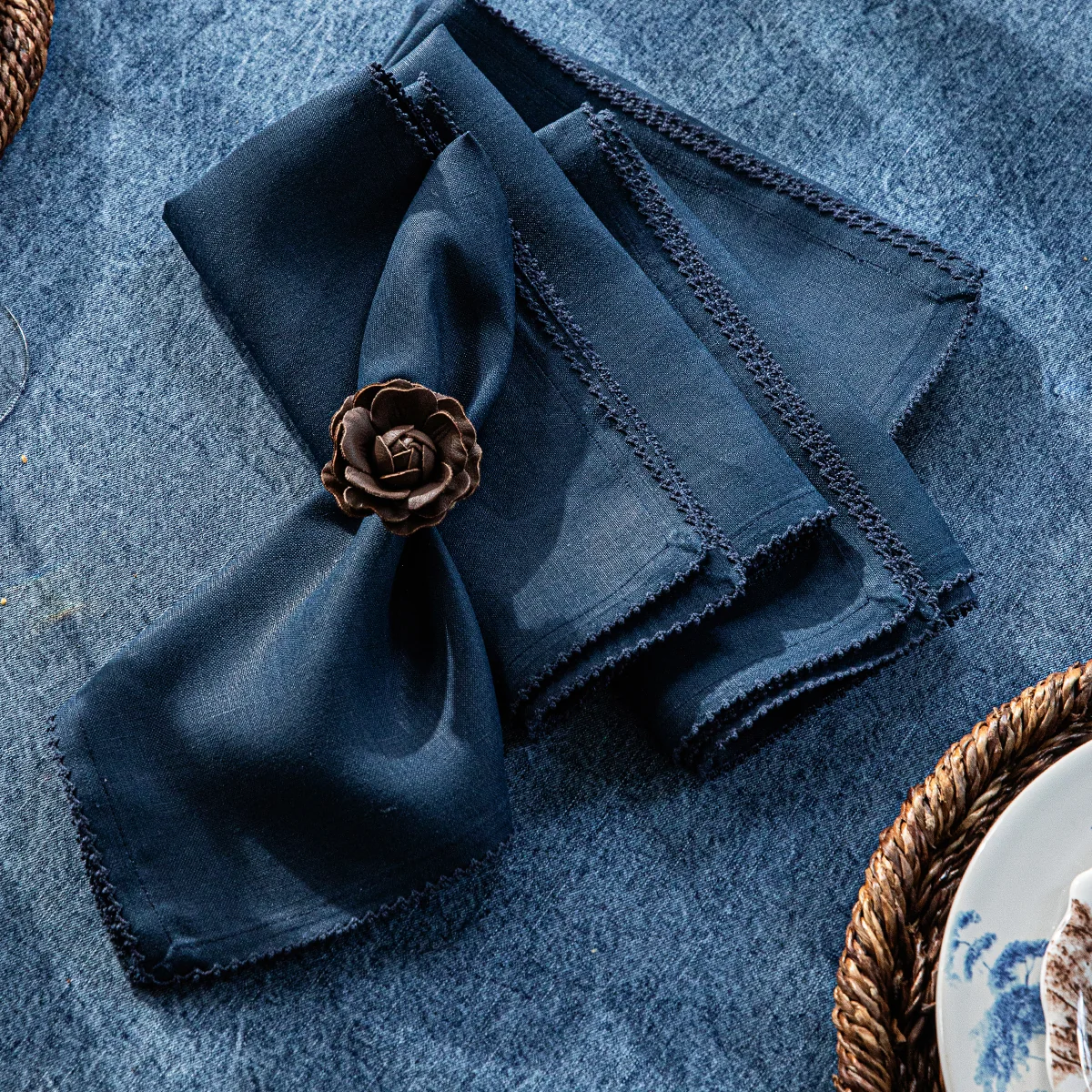 navy linen napkins with subtle scallop trim shown folded on a denim tablecloth