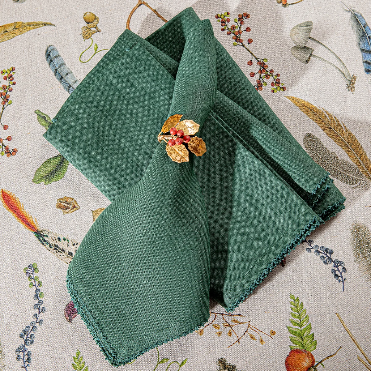 green linen napkins with subtle scallop trim shown folded on a whimsical woodland tablecloth