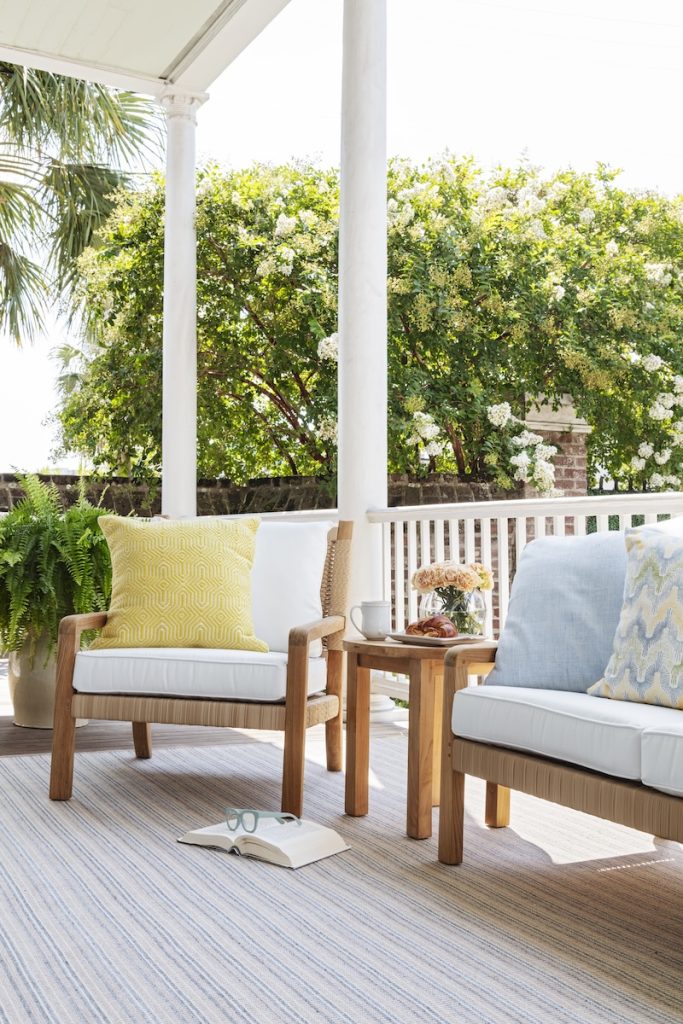 A small outdoor living space on a Charleston porch, styled as an outdoor workspace with deep seated outdoor furniture from GDC Homes' furniture in Mt Pleasant SC