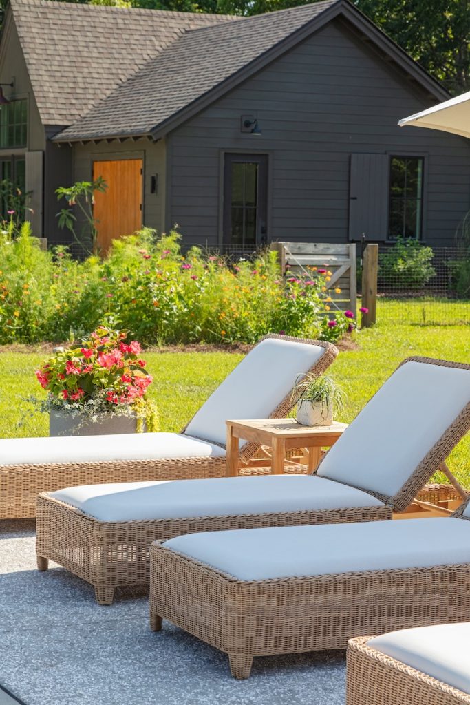A small backyard lounge area styled with outdoor wicker chaise lounge from GDC Home's furniture stores Charleston SC