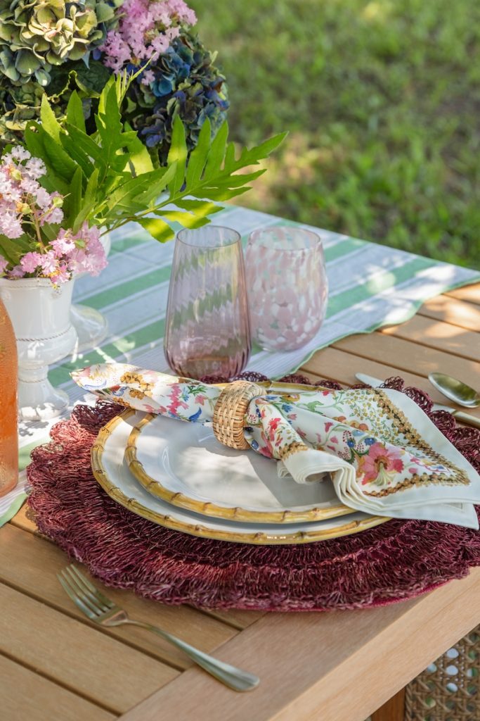 A cozy breakfast nook in a small outdoor living space, styled with colorful tabletop pieces and a dinnerware set from charleston home decor store GDC