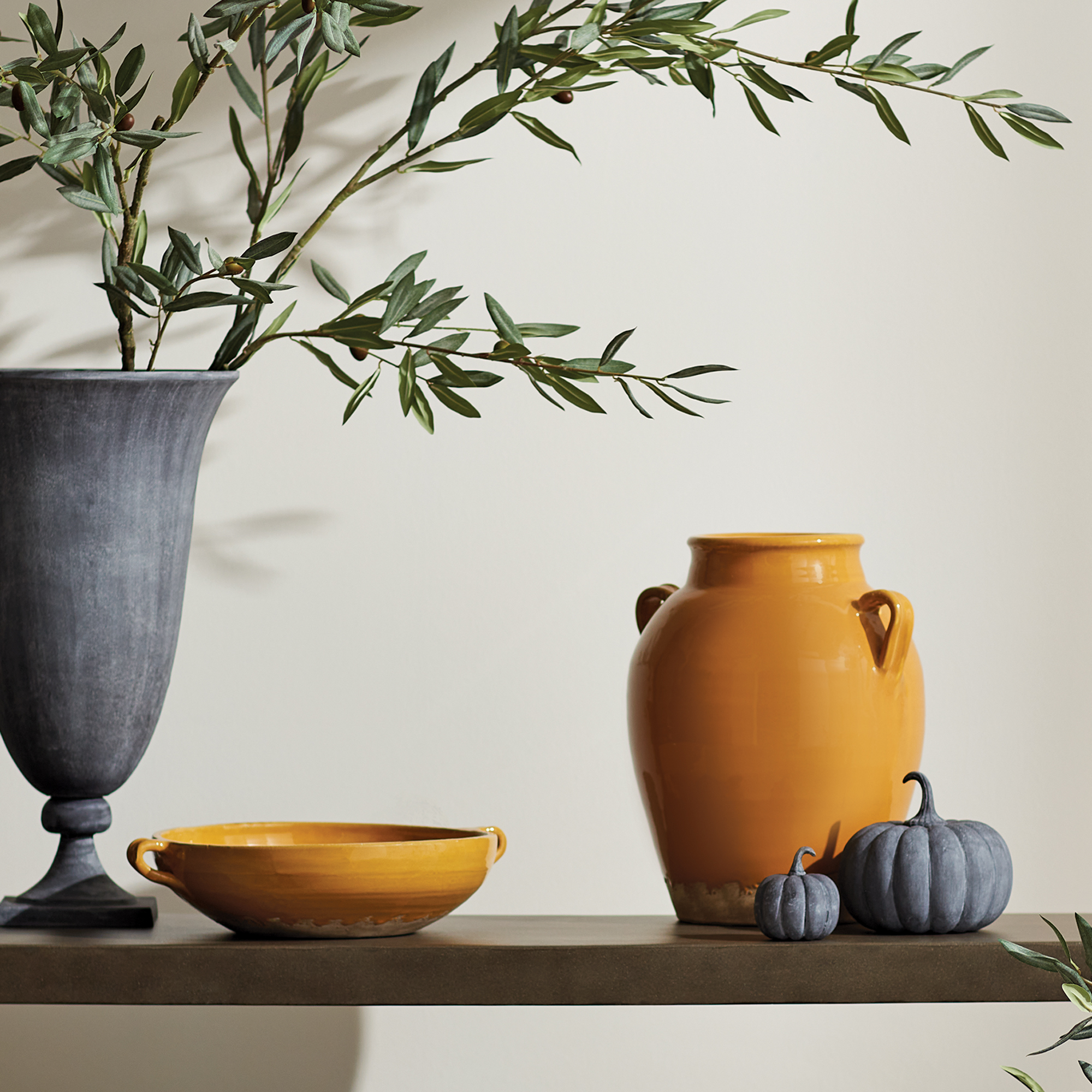 lifestyle image of golden ochre decorative terracotta vase and bowl, slate gray vase with greenery, slate gray decorative pumpkins