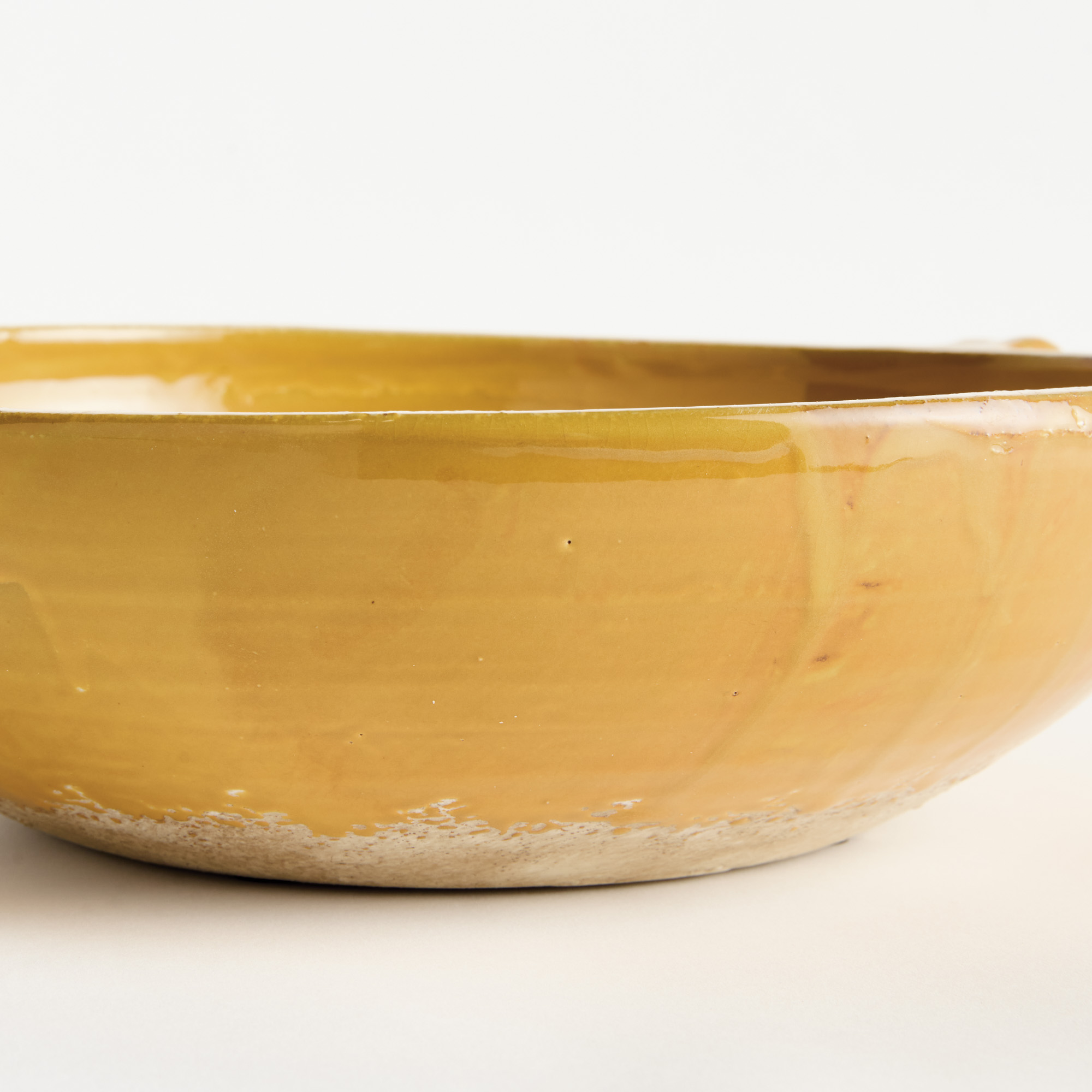 detail of decorative terracotta bowl with handles and golden ochre glaze