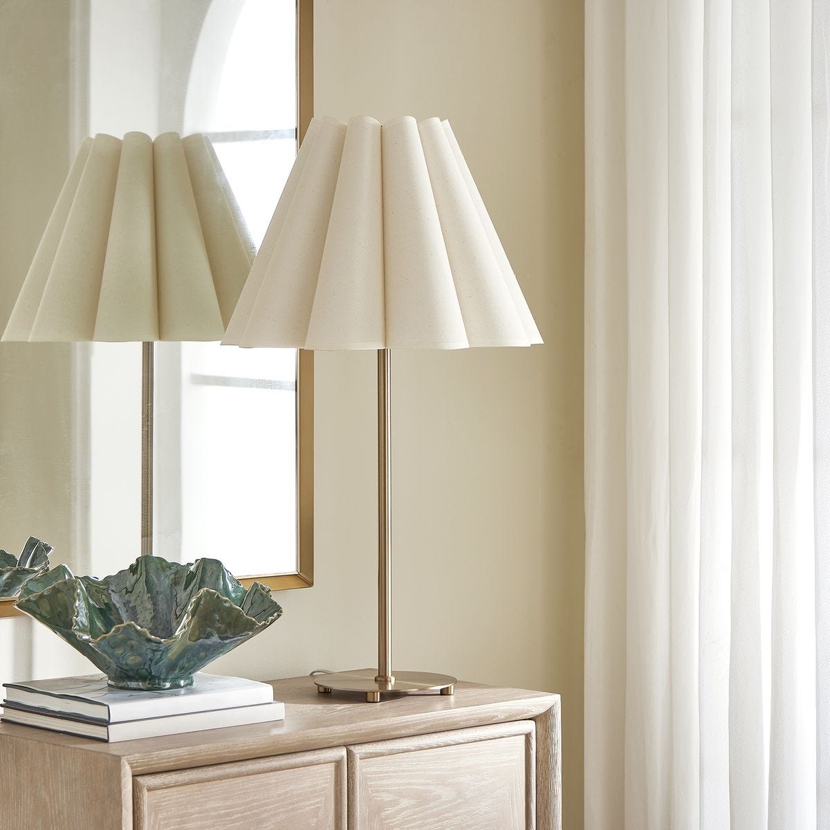 lifestyle image of a brass lamp with white scalloped shade