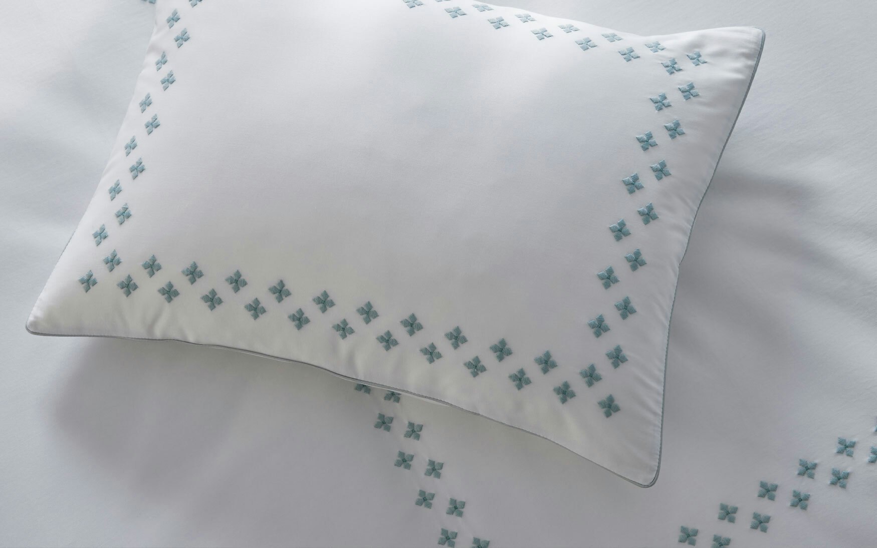 detail of white pillow sham and duvet with pool embroidered Moroccan tilework design