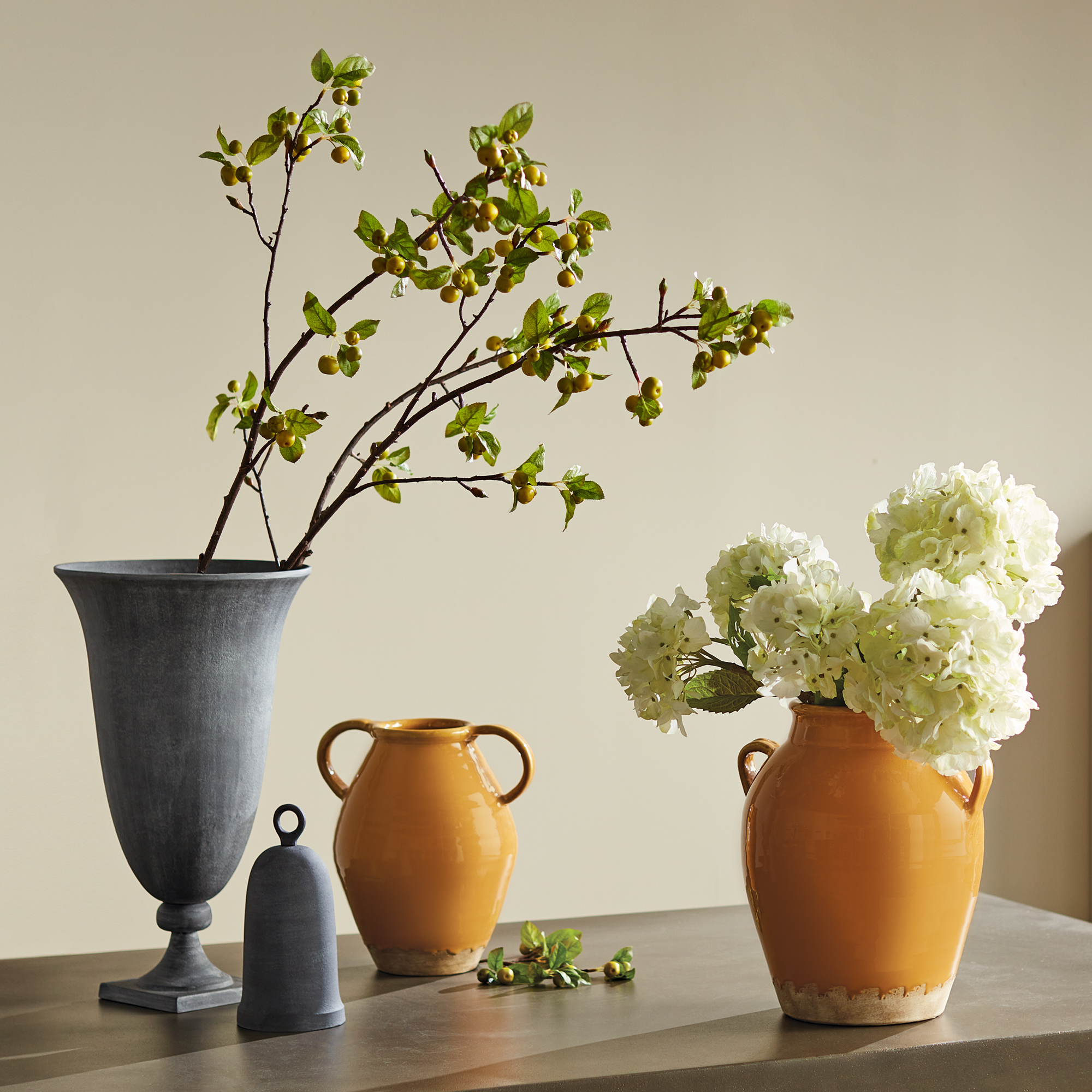 lifestyle image of decorative terracotta vases with flowers, golden ochre glaze