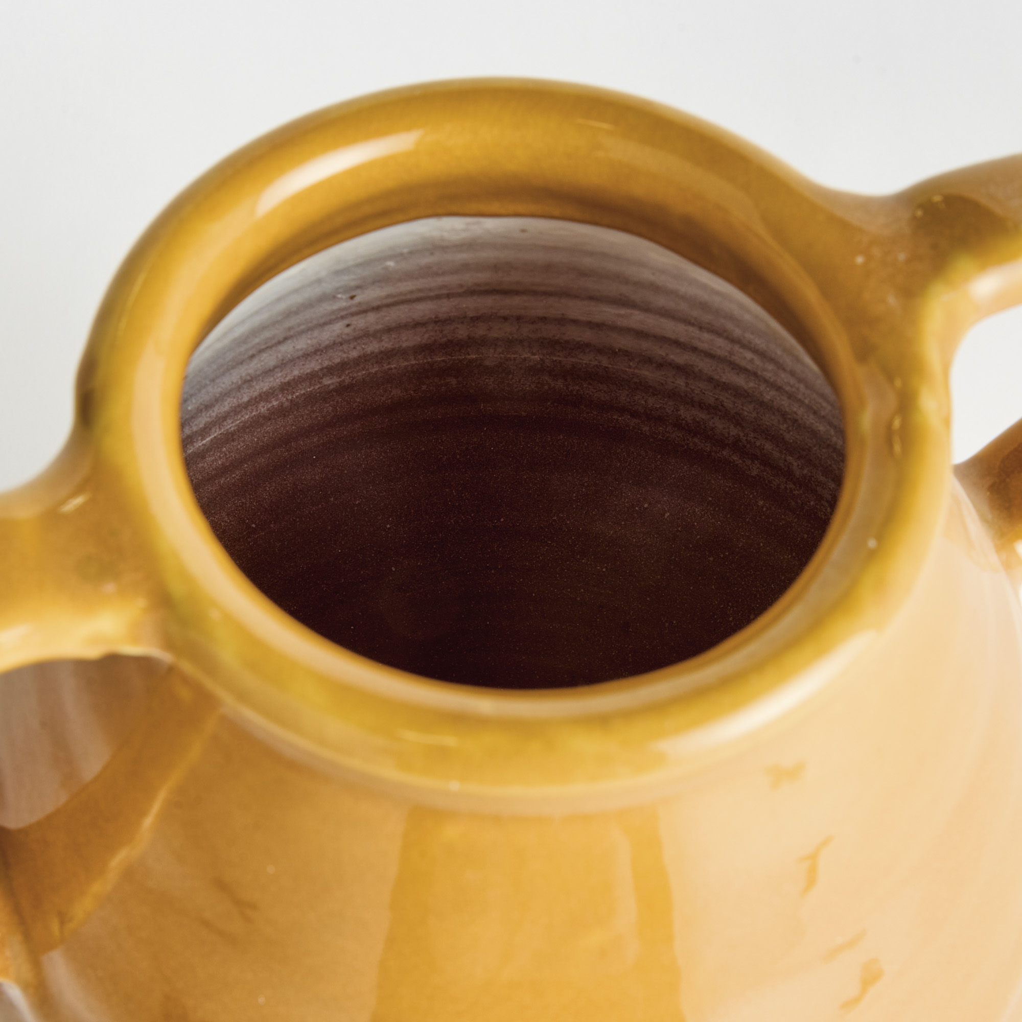 detail of decorative terracotta vase with handles and golden ochre glaze