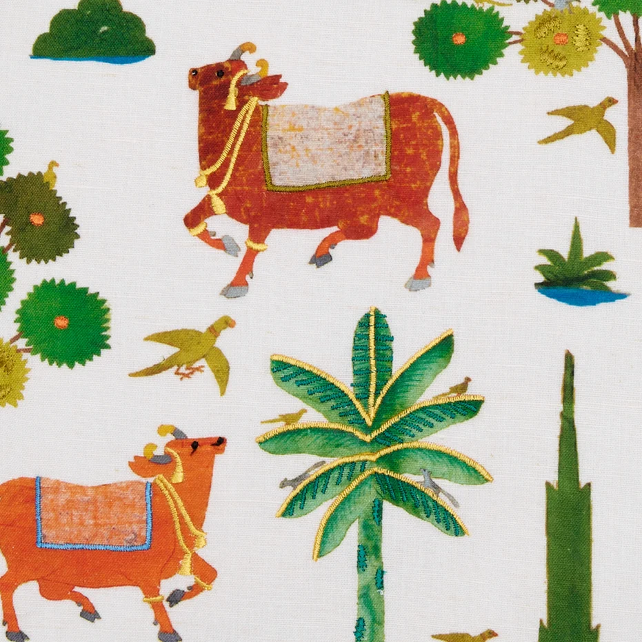 detail of decorative pillow with painted and embroidered cows and palm trees