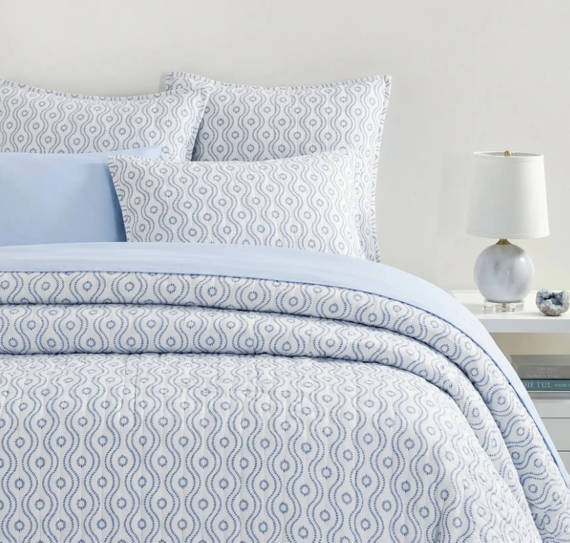 lifestyle image of block print quilt and shams, dotted wave, light blue bedding, coastal