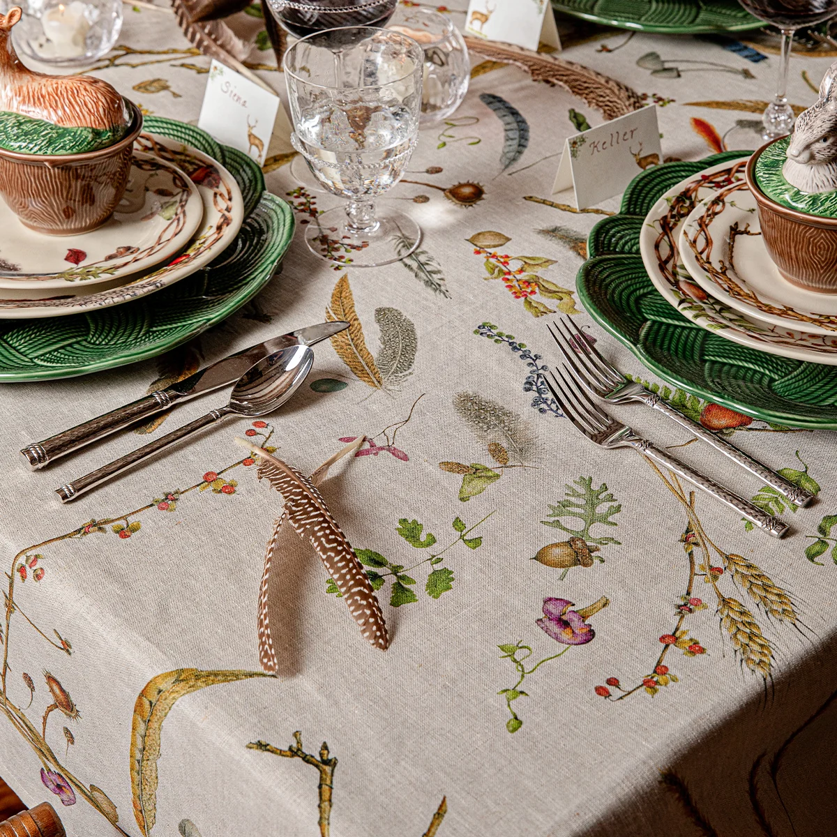 holiday table set with woodland inspired plates, bowls, and tablecloth