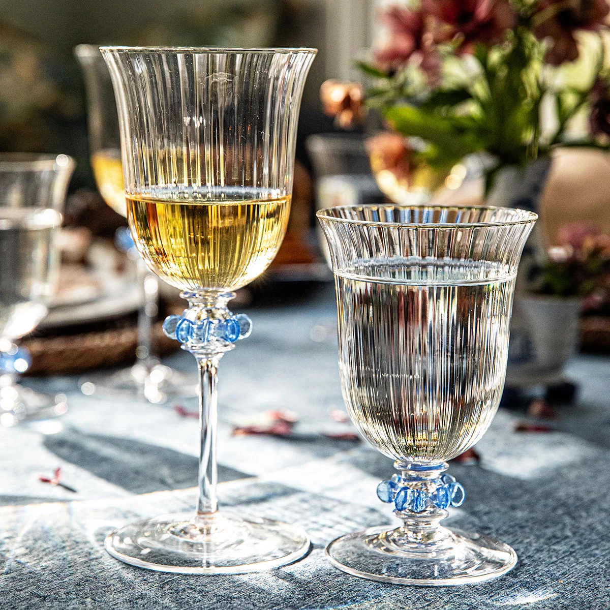 wine glass and goblet with tulip shaped silhouettes and jewelry-like glass ruffles in blue on a set holiday table