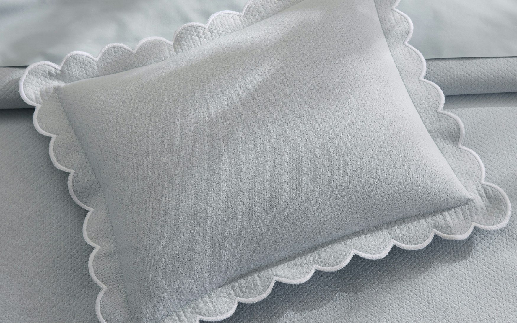 detail of diamond patterned icy blue-grey sham with scalloped edges