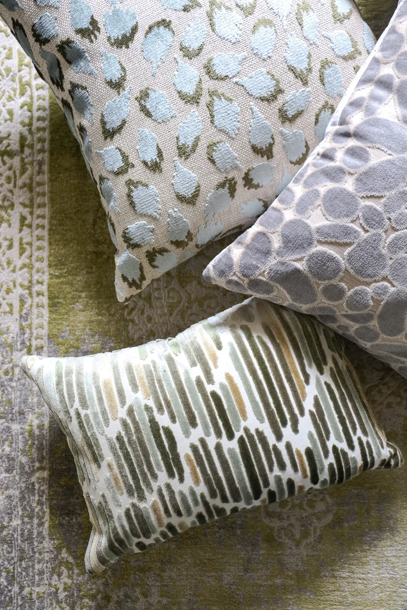 three cut velvet decorative pillows on a green rug