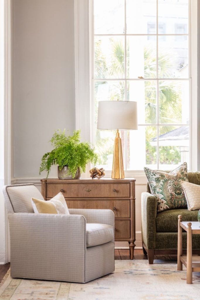 A beige accent chair that does not match the sofa, which is green, styled with furniture mt pleasant sc residents can find at their local GDC furniture store
