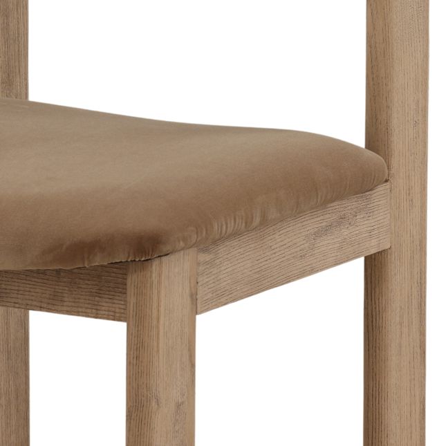 detail of a dining chair with a wood frame and light brown velvet seat