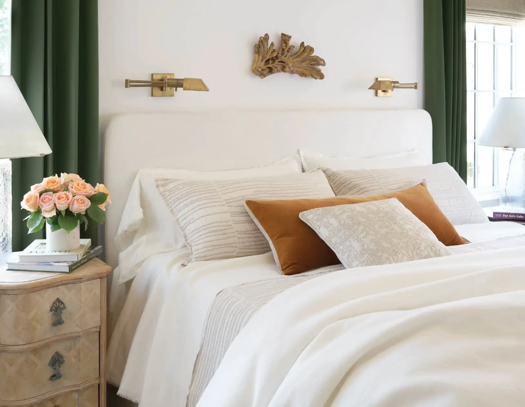 lifestyle image of bed made up in neutral linens and an orange velvet bolster pillow