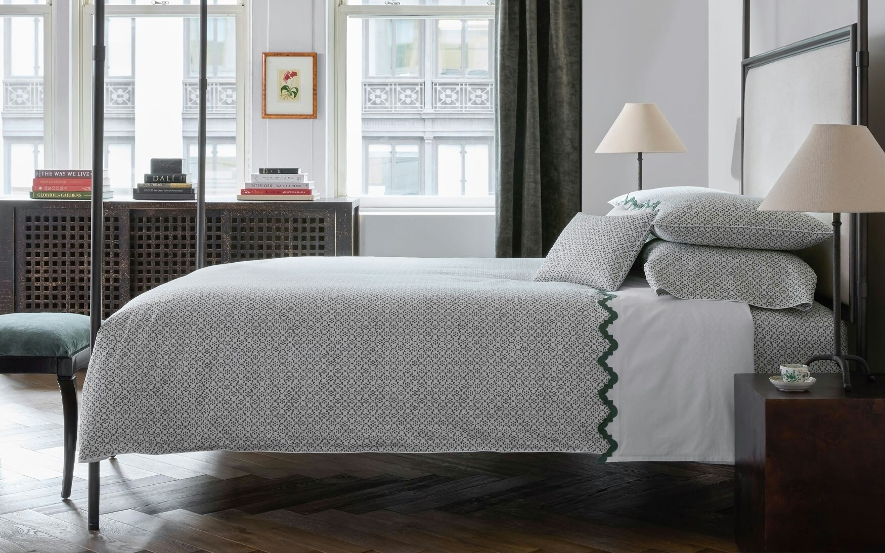 room with a bed made up in green block print and scalloped green bedding