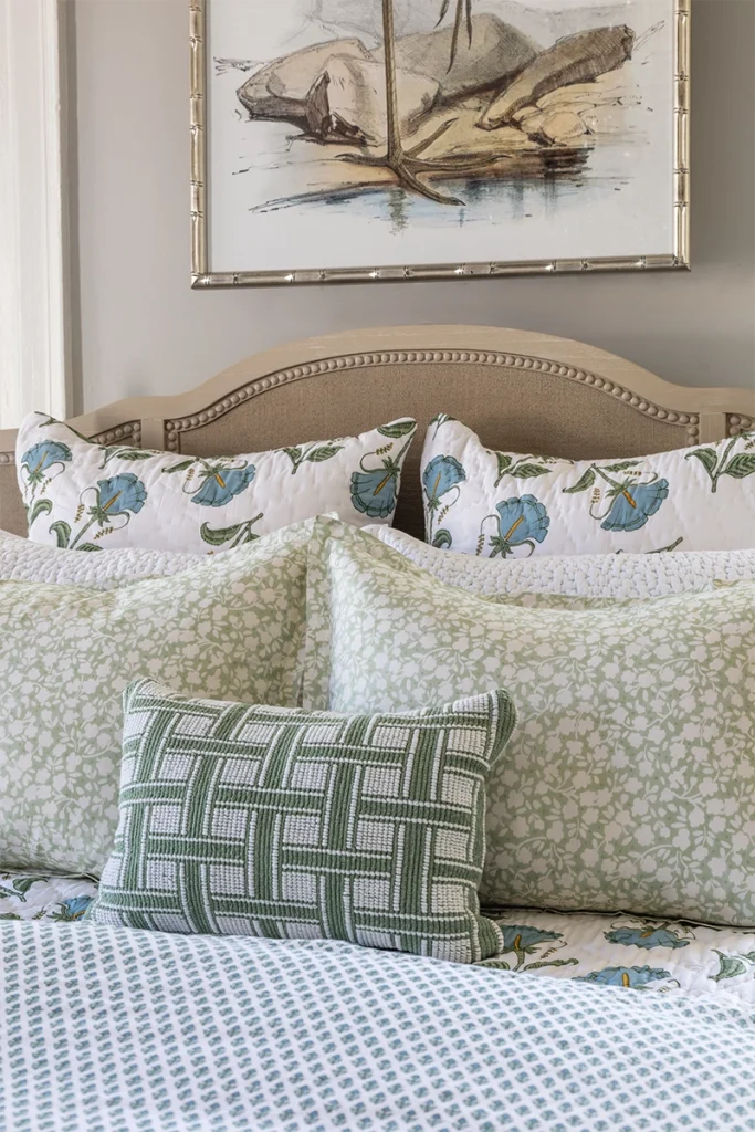 Bedding with mixed prints and patterns in soft greens, blues, and neutrals, sourced from GDC Home's bedding stores in Charleston, SC