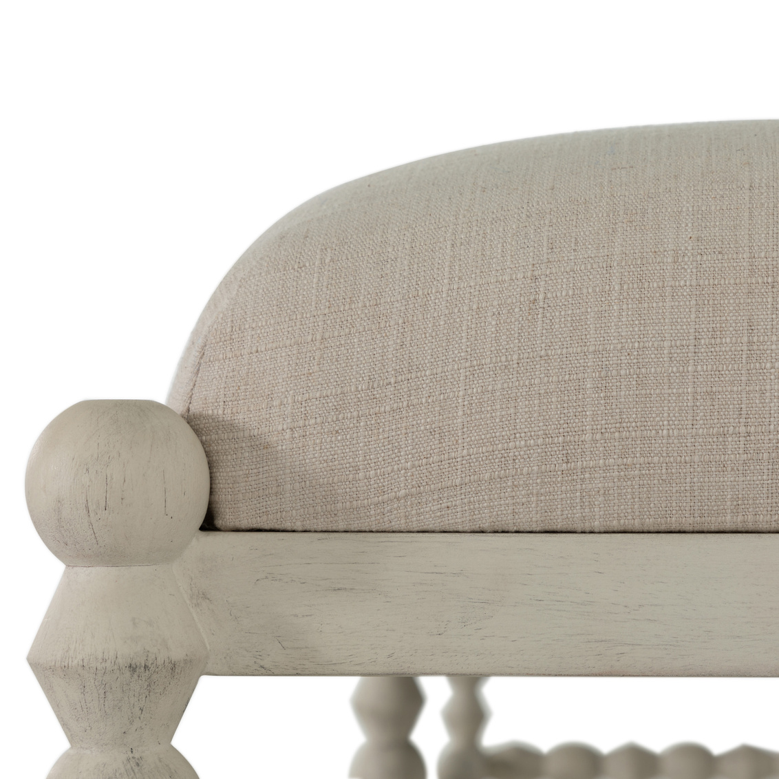 detail of neutral fabric and antique white finish on a bobbin style ottoman