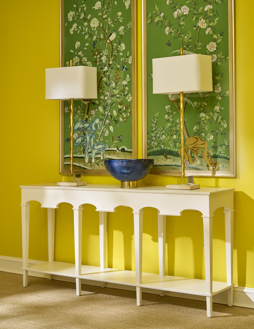 bright yellow room with a white console, two buffet lamps, and green chinoiserie art