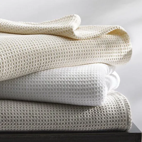 A stack of folded waffle weave blankets in neutral colors