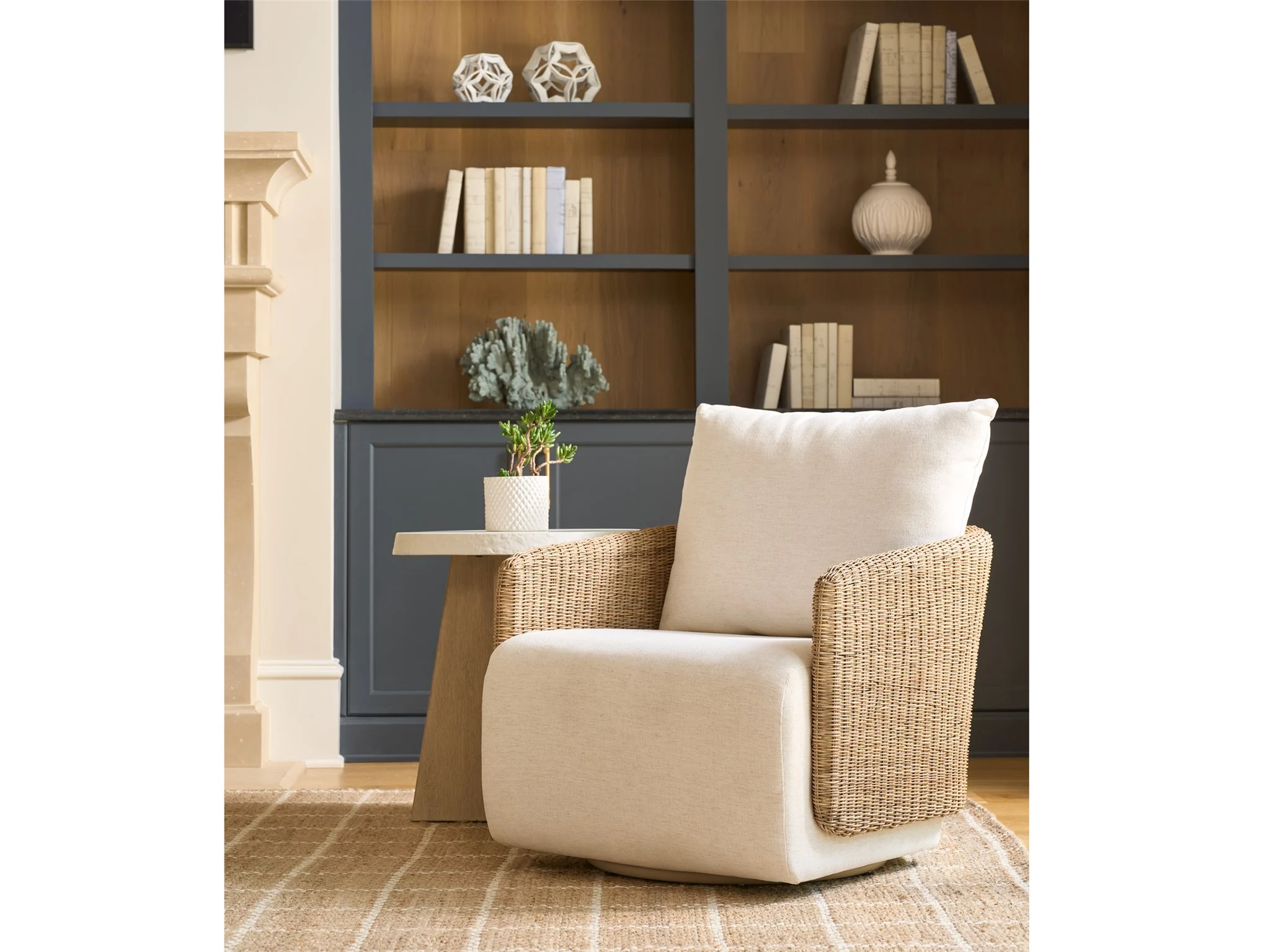 small scale off white and woven swivel chair next to a spot table in a room with painted bookcase